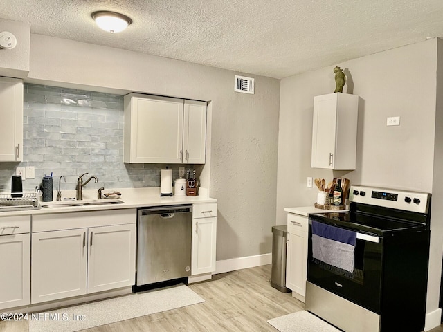 1425 Domas Dr, Jacksonville, FL 32211 - kitchen featuring stainless steel appliances, a sink, light wood-style flooring, a textured ceiling, and light countertops
