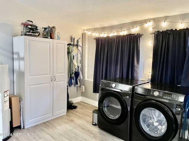 clothes washing area with a textured ceiling, light wood-type flooring, washing machine and dryer, and water heater