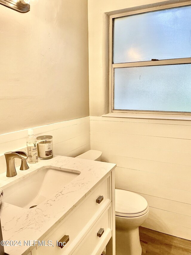 1425 Domas Dr, Jacksonville, FL 32211 - bathroom with wood finished floors, vanity, toilet, a wainscoted wall, and tile walls