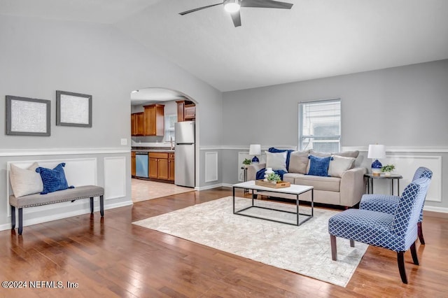 living room with light hardwood / wood-style floors, ceiling fan, and vaulted ceiling