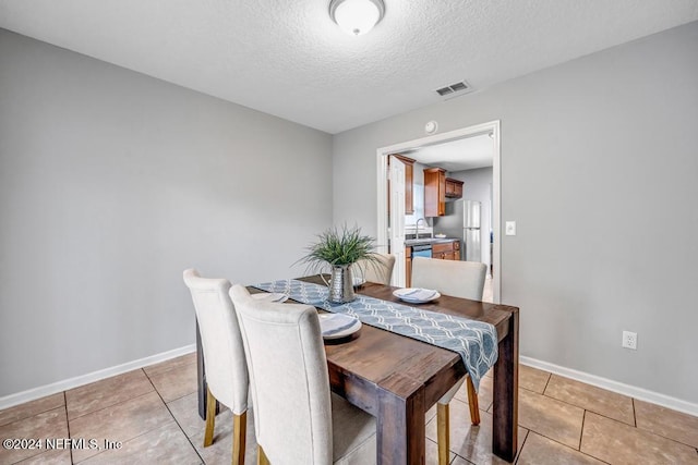 tiled dining area with sink and a textured ceiling