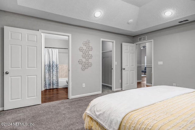 carpeted bedroom featuring a spacious closet, ensuite bath, a closet, and a textured ceiling