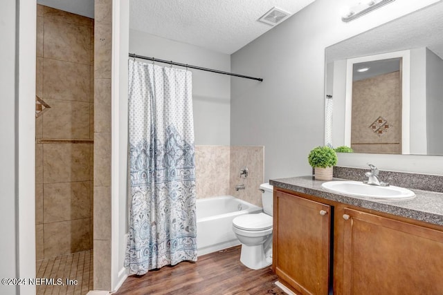 full bathroom with a textured ceiling, wood-type flooring, toilet, shower / bath combo, and vanity