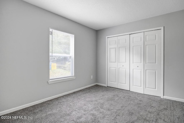 unfurnished bedroom featuring a textured ceiling, carpet flooring, and a closet