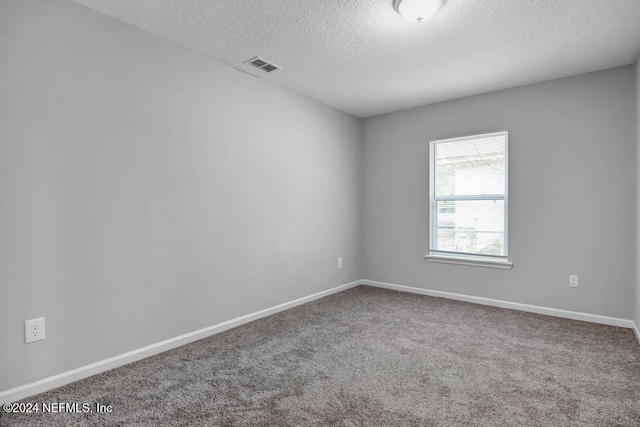 carpeted empty room featuring a textured ceiling