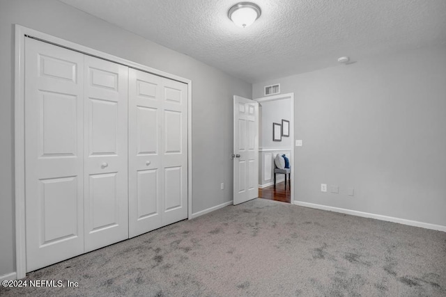 unfurnished bedroom with a closet, carpet floors, and a textured ceiling