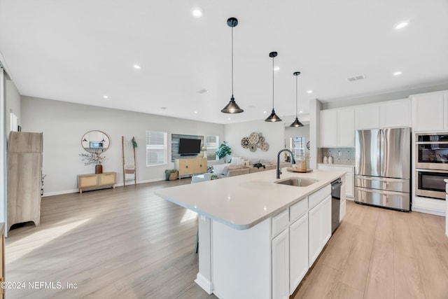 kitchen featuring an island with sink, stainless steel appliances, plenty of natural light, and sink