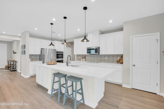 kitchen featuring white cabinetry, sink, stainless steel appliances, an island with sink, and light wood-type flooring