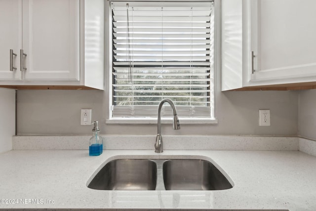 kitchen with sink, light stone counters, and white cabinets