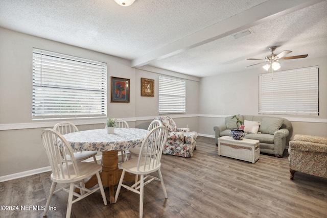 dining space featuring a textured ceiling, wood-type flooring, ceiling fan, and beam ceiling