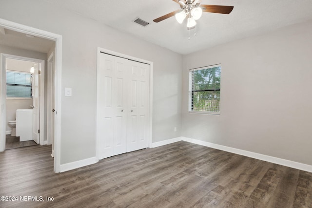 unfurnished bedroom with connected bathroom, a closet, wood-type flooring, and ceiling fan