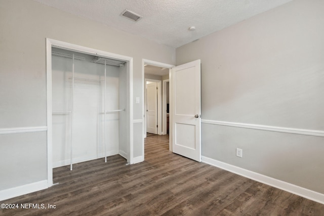 unfurnished bedroom featuring a closet, a textured ceiling, and dark hardwood / wood-style floors