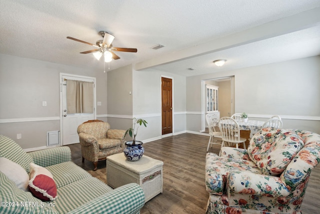 living room featuring dark wood-type flooring, a textured ceiling, and ceiling fan