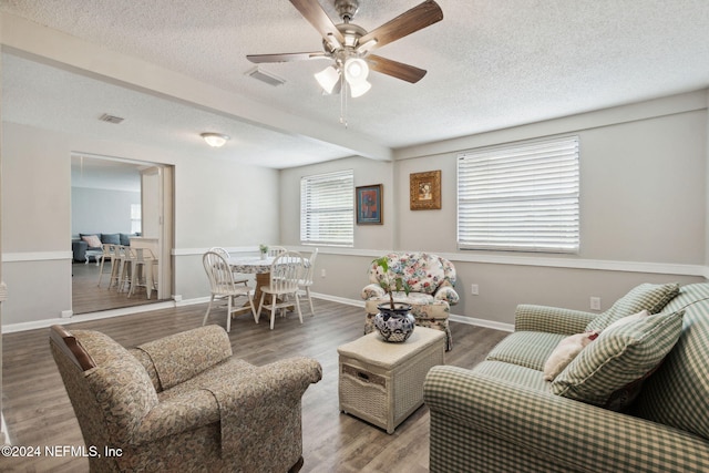 living room featuring hardwood / wood-style flooring, ceiling fan, and a textured ceiling