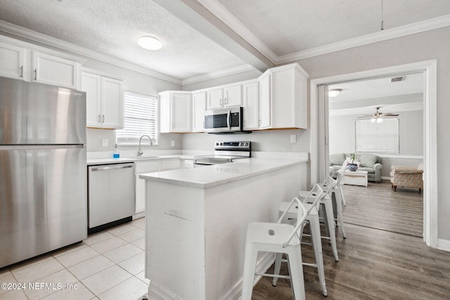 kitchen with white cabinetry, kitchen peninsula, appliances with stainless steel finishes, and a textured ceiling