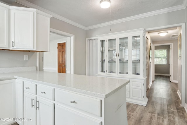 kitchen with white cabinetry, a textured ceiling, crown molding, and light wood-type flooring