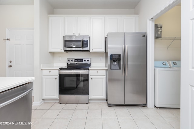 kitchen featuring stainless steel appliances, washing machine and dryer, white cabinets, and light tile patterned floors