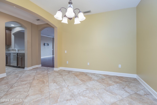 spare room featuring crown molding and a chandelier