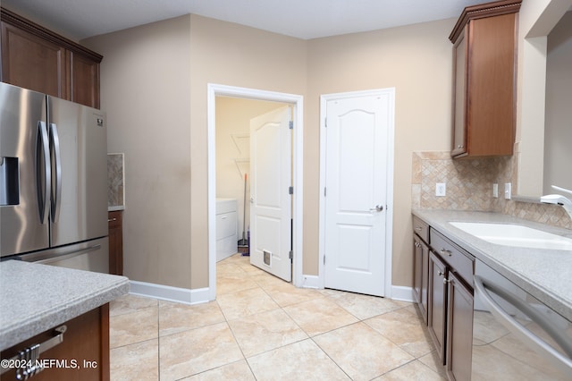 kitchen with stainless steel appliances, light tile patterned flooring, sink, and tasteful backsplash