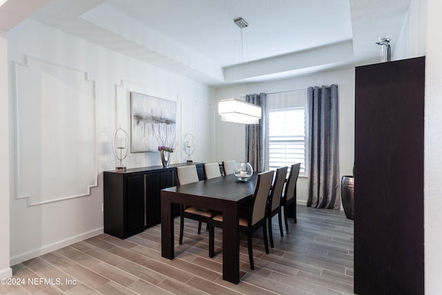 dining area with hardwood / wood-style flooring and a raised ceiling