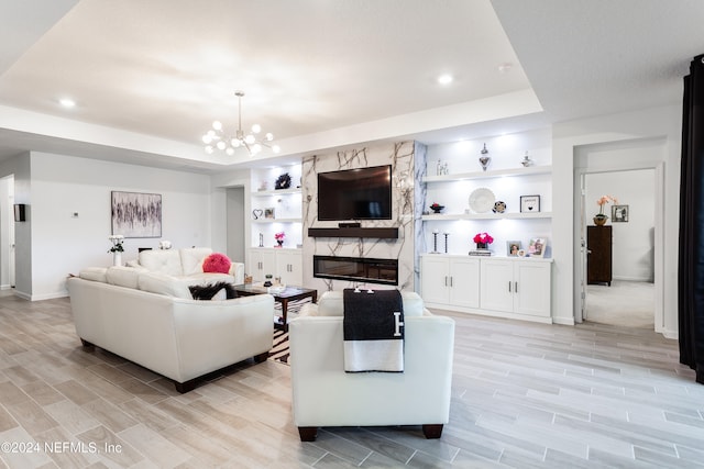 living room with a tray ceiling, built in features, and a chandelier