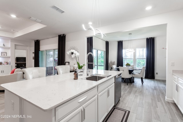 kitchen with a center island with sink, hanging light fixtures, and sink