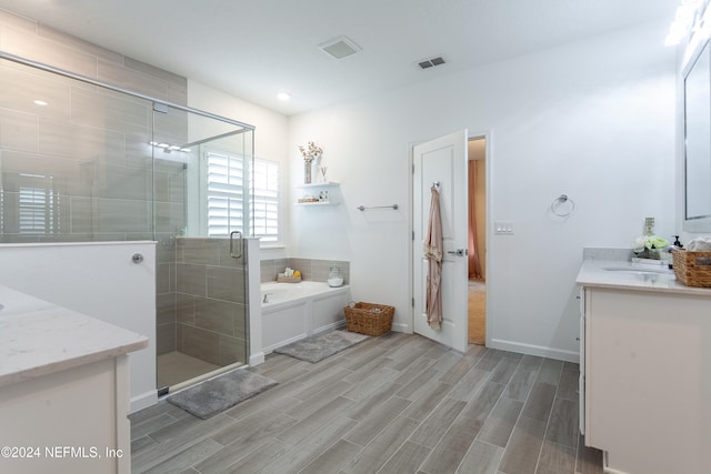 bathroom featuring hardwood / wood-style floors, vanity, and independent shower and bath