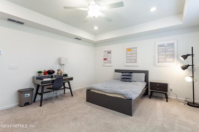 bedroom with ceiling fan, a raised ceiling, and light carpet