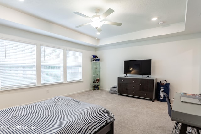 carpeted bedroom featuring a tray ceiling and ceiling fan