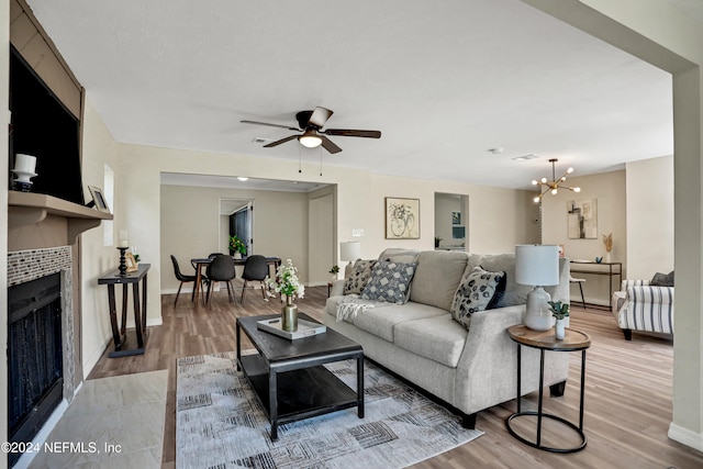 living room with hardwood / wood-style floors, ceiling fan with notable chandelier, and a tile fireplace