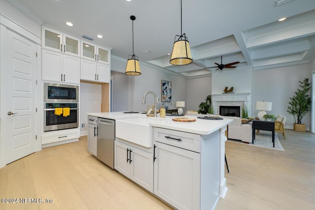 kitchen featuring pendant lighting, white cabinets, stainless steel appliances, and a center island with sink