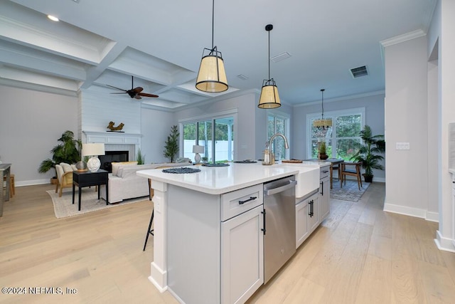 kitchen featuring dishwasher, a kitchen island with sink, decorative light fixtures, and coffered ceiling