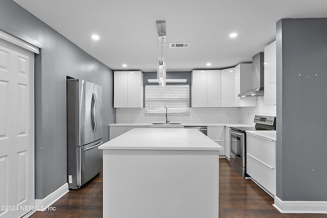 kitchen with white cabinetry, appliances with stainless steel finishes, wall chimney exhaust hood, a center island, and dark hardwood / wood-style flooring