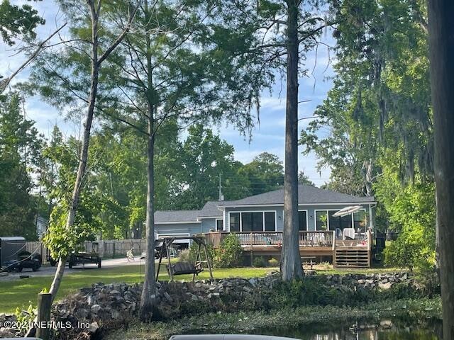 rear view of house featuring a deck and a yard