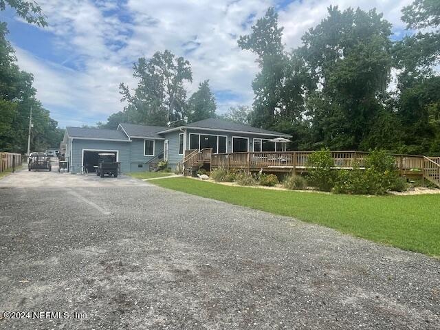 view of front of property with a front yard, a wooden deck, and a garage