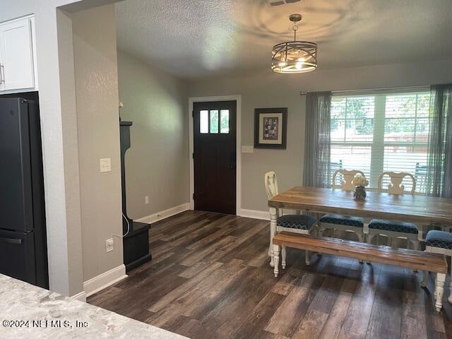 dining area featuring a textured ceiling, dark hardwood / wood-style floors, and a chandelier