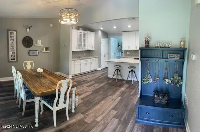 dining area featuring vaulted ceiling, a notable chandelier, and dark hardwood / wood-style flooring