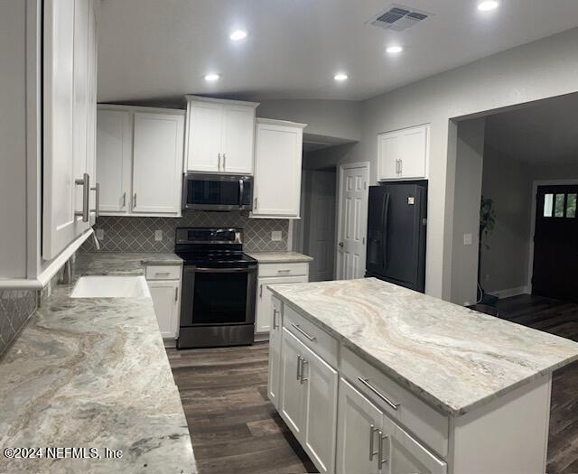 kitchen with white cabinetry, light stone counters, stainless steel appliances, and dark hardwood / wood-style flooring