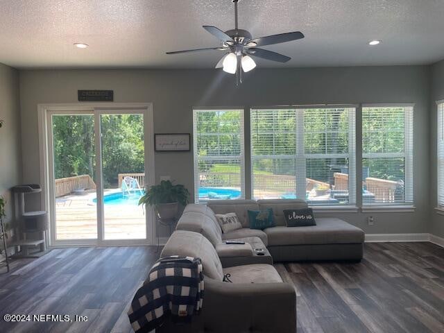 living room featuring dark wood-type flooring, a textured ceiling, and ceiling fan