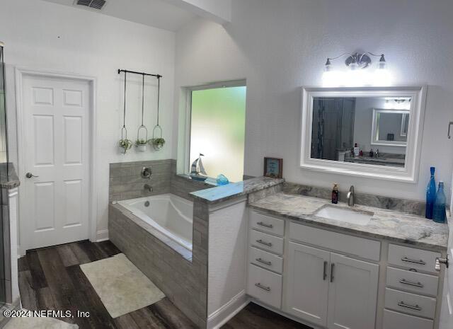 bathroom with vanity, wood-type flooring, and tiled bath