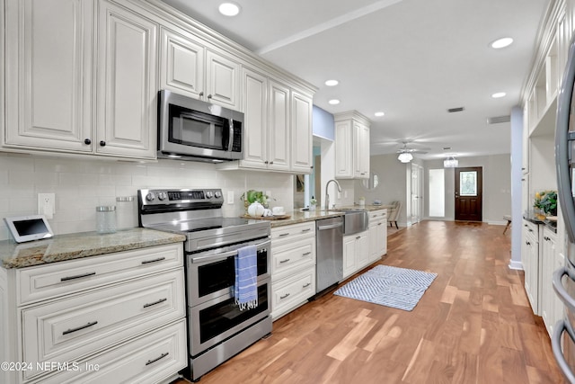 kitchen featuring white cabinetry, appliances with stainless steel finishes, backsplash, and light wood-type flooring