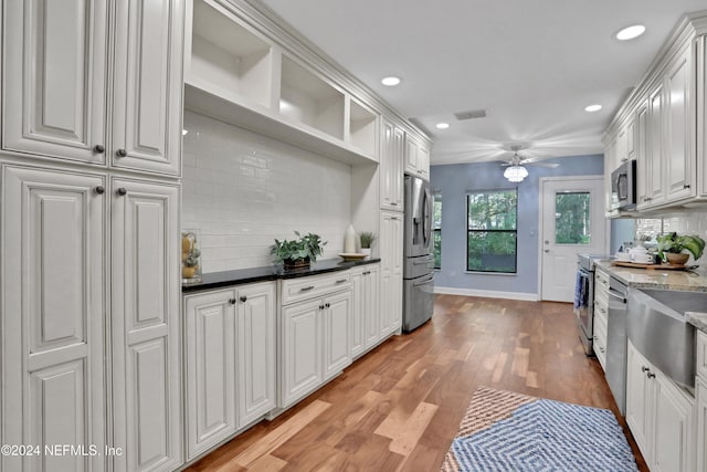 kitchen featuring stainless steel appliances, light wood-type flooring, white cabinetry, backsplash, and ceiling fan