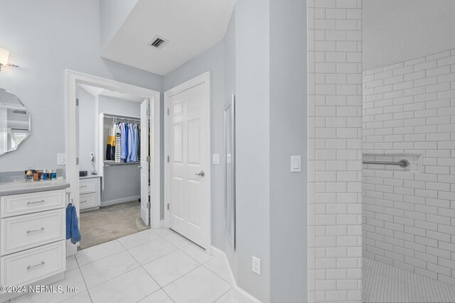 bathroom with vanity, tile patterned flooring, and a tile shower