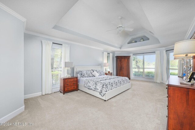 carpeted bedroom featuring multiple windows, a raised ceiling, ceiling fan, and crown molding