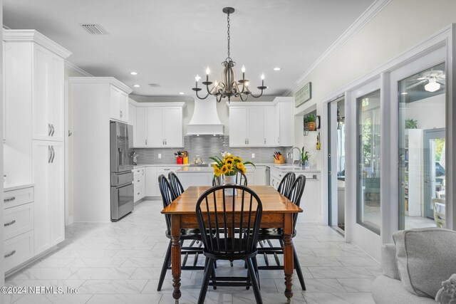 dining area with ornamental molding, ceiling fan with notable chandelier, and sink