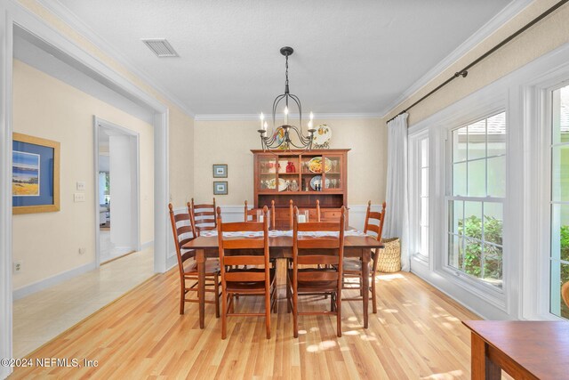 dining area featuring light hardwood / wood-style floors, crown molding, and a notable chandelier