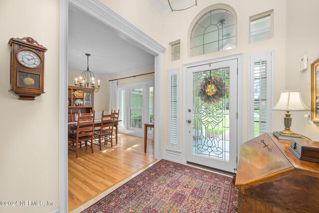 foyer with a chandelier, wood-type flooring, and ornamental molding