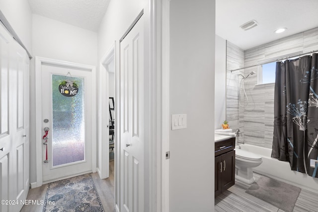 full bathroom featuring shower / bath combo, vanity, hardwood / wood-style flooring, toilet, and a textured ceiling