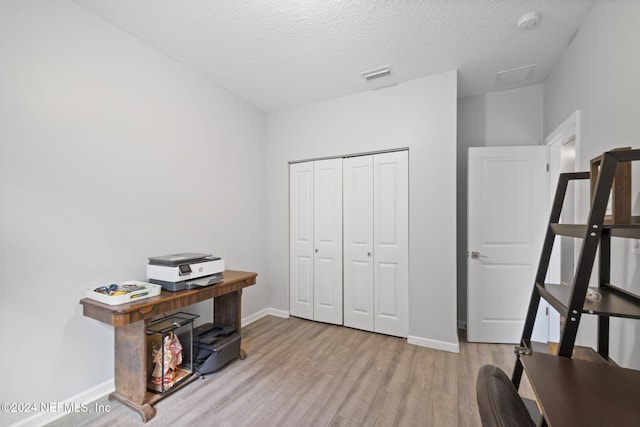 office area with a textured ceiling and light hardwood / wood-style flooring