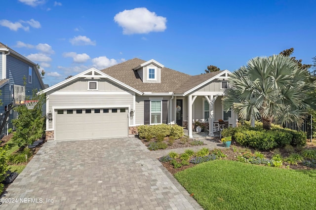 view of front of property featuring a front lawn, a garage, and covered porch